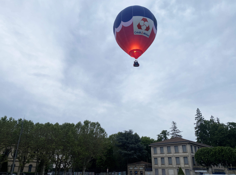Le ballon ultra léger et ses passagers s'envolent sans effort au-dessus de la cité pavée