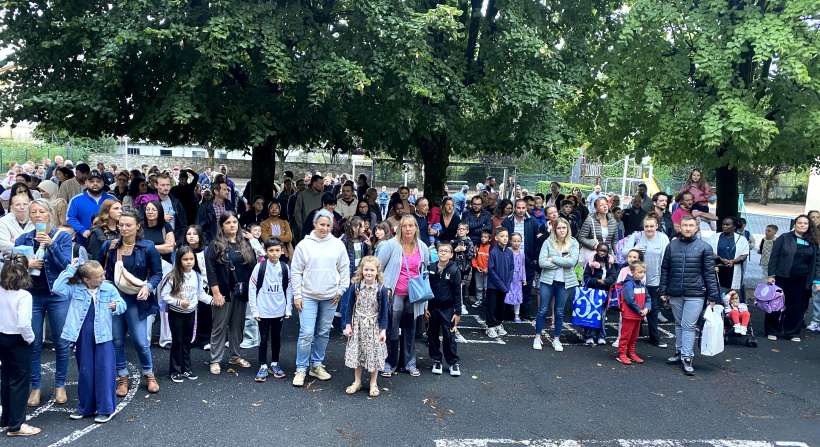 Les parents en train d'écouter le discours de la direction dans la cour de l'école.